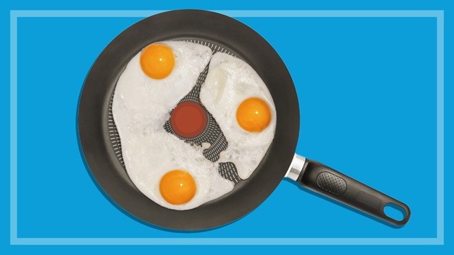 three eggs frying in a non-stick frypan on a blue background